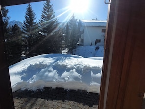A snow-covered landscape with a building and trees in the background.