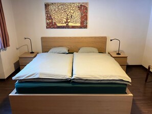 Ein Doppelbett mit Holz Kopfteil, zwei Nachttische mit Lampen und ein Wandbild.