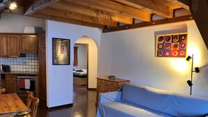 Una habitación acogedora con una mesa de comedor de madera, un sofá y una cocina al fondo.