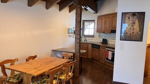 Una mesa de comedor de madera con sillas, una cocina con armarios de madera y un cuadro en la pared.