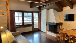 Una sala de estar acogedora con un sofá, una mesa de madera, una chimenea y un televisor.
