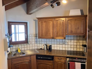 Cozinha com armários de madeira, painel de azulejos, pia de aço inoxidável, lava-louças e forno.