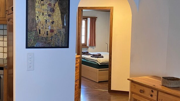 Una habitación con techo de madera, un cuadro en la pared, una cama con cubrecama verde y armarios de madera.