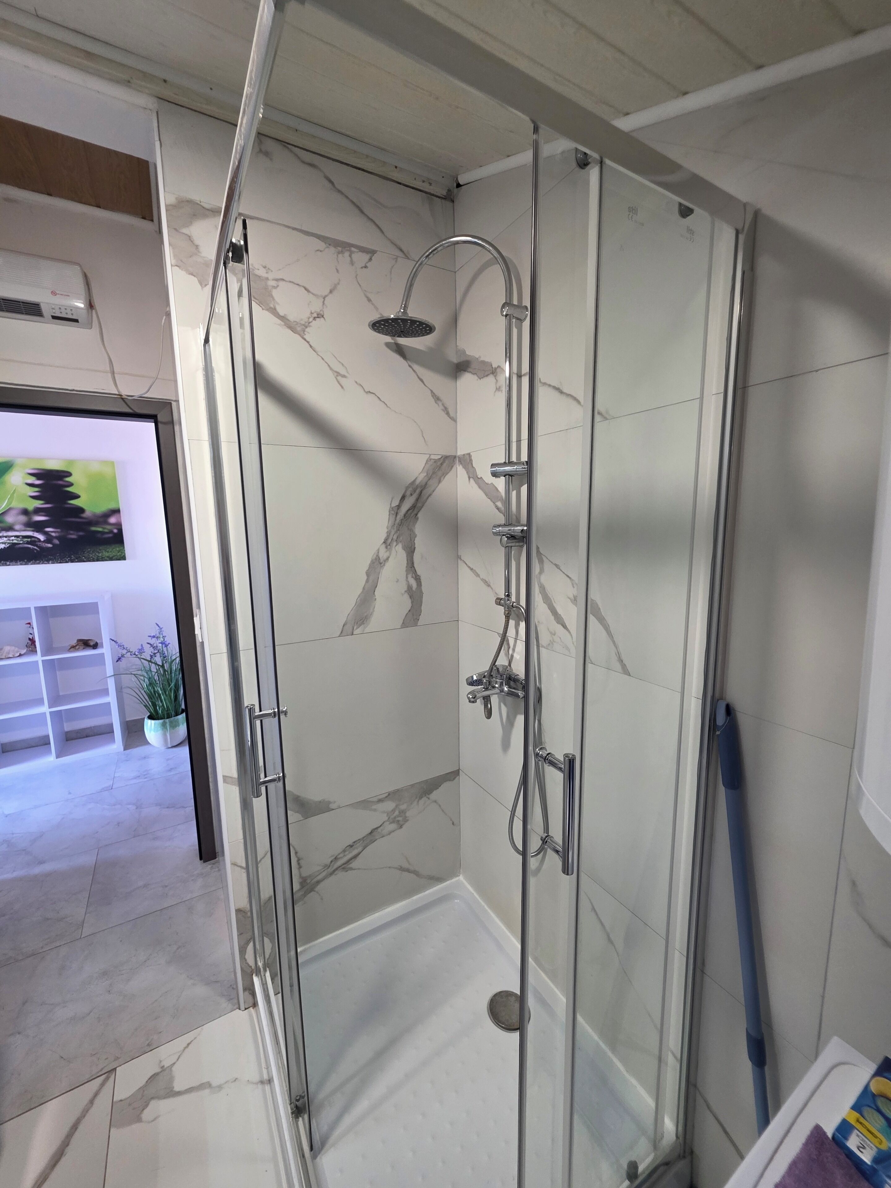 A glass-enclosed shower with a handheld showerhead, a handheld showerhead, and a wall-mounted showerhead.