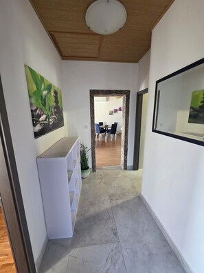 A hallway with a white wall, a ceiling light, and a door leading to a dining area with chairs and a table. - Villa Sunrise – Private Pool & Ocean View (Novi Vinodolski)