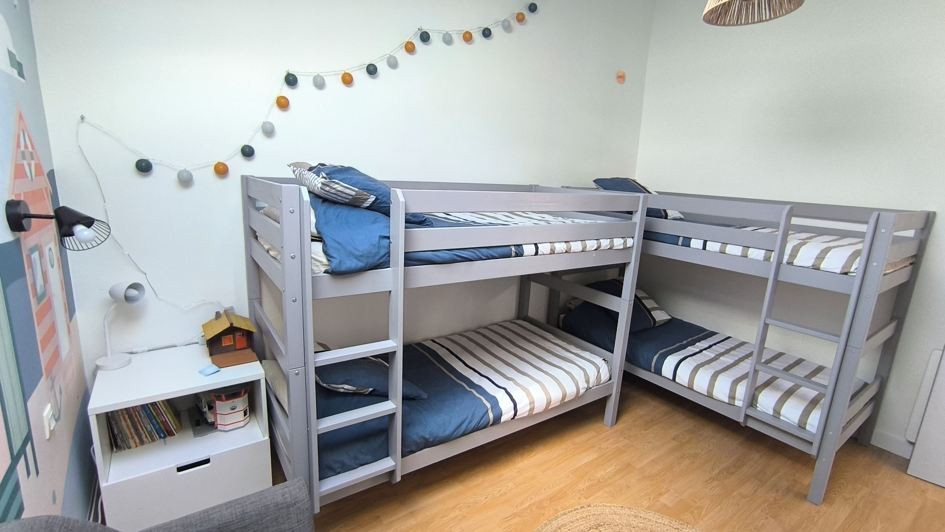 A bunk bed room with a desk, a lamp, and a wall decoration.