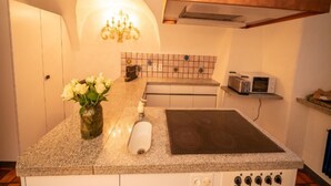 Una cocina con encimera de granito, un tostador de acero inoxidable, un microondas, una estufa y un florero con flores blancas.