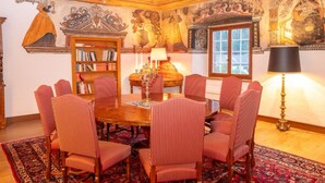 Una habitación con una mesa de madera, sillas a rayas rojas, una estantería, una lámpara y una ventana.