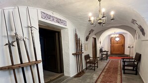 Un pasillo con puerta de madera, un candelabro y una alfombra estampada.