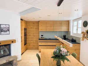 Eine moderne Küche mit Holzausstattung, einer schwarzen Arbeitsplatte und einem Esstisch mit Stühlen.