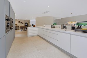 A modern kitchen with a central island, built-in oven, and a dining area with a pool table. - Perched above Matlock Bath, 37 Steps is a stylish upside-down home designed to make the most of its incredible views across the valley. With a sociable open-plan living space, four ensuite bedrooms, and a showstopping terrace with hot tub. (Matlock Bath)