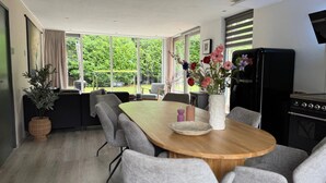 Una cocina moderna con comedor, ventanas amplias y vista a la vegetación.