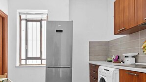 Una cocina con un refrigerador de acero inoxidable, una lavadora y armarios de madera.