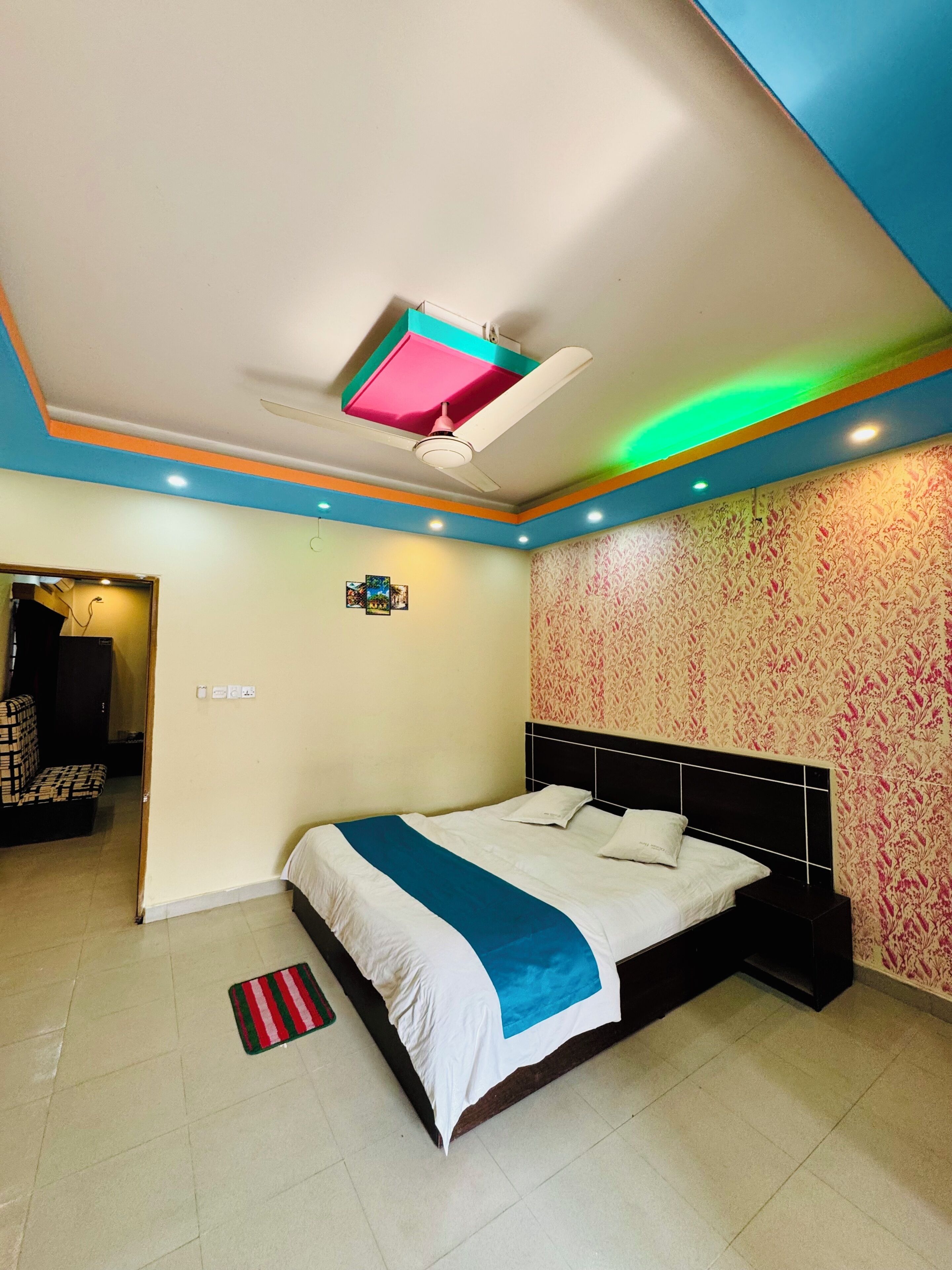 A bedroom with a bed, a ceiling fan, and a patterned wall.