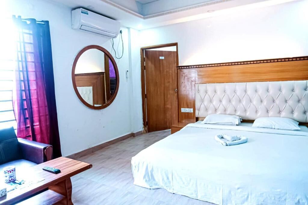 Une chambre d’hôtel avec un lit, un miroir rond, une porte en bois et une petite table.