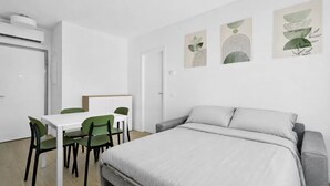 Un dormitorio moderno con una cama, un escritorio y sillas. Hay tres obras de arte en la pared sobre la cama.