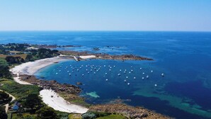 An aerial view of a coastal area with a beach, boats, and houses. - -OPALE- Studio with ocean view, balcony, and parking (Concarneau)