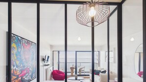 A modern interior with a large window, a unique light fixture, and a colorful abstract painting. - -OPALE- Studio with ocean view, balcony, and parking (Concarneau)