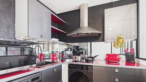 A modern kitchen with a built-in microwave, red appliances, and a stainless steel range hood. - -OPALE- Studio with ocean view, balcony, and parking (Concarneau)