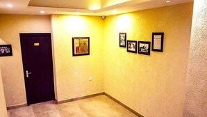 Un pasillo con puerta, cuadros en la pared y una lámpara.
