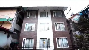 Un edificio de varios pisos con entrada central, múltiples ventanas y un balcón visible.
