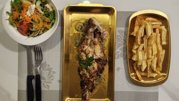 A meal consisting of grilled fish, a side of fries, and a salad on a table with a placemat.