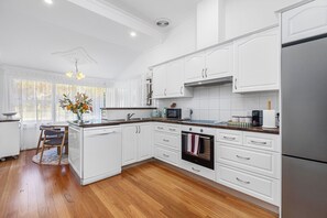 A modern kitchen with white cabinetry, a stainless steel refrigerator, and a built-in oven.