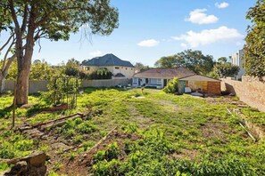 A residential backyard with a house, a tree, and a fence.