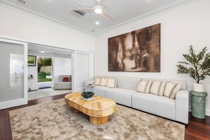 A modern living room with a large abstract painting, a grey sofa, a round coffee table, and a potted plant. - Charming Garden Retreat: Peaceful Oasis with Vintage Character (Dalkeith)