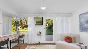 Ein Zimmer mit Esstisch, Stühlen, einer Couch, einem Teppich und Blick durch eine Tür.