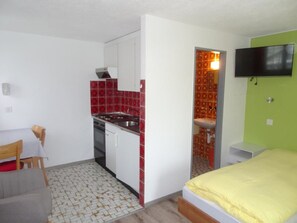 A compact room with a kitchenette, a bed, a TV, and a small table. - Mon Etoile, (Grächen), by Interhome (Grächen)