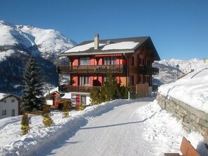 A two-story chalet with a balcony, set against a snowy mountain backdrop. - Mon Etoile, (Grächen), by Interhome (Grächen)
