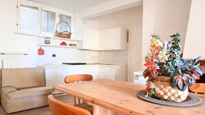 A compact kitchen with white cabinets, a wooden dining table, and a sofa. -  M472 - Marcelli, comfortable terraced house near the sea (Marcelli)