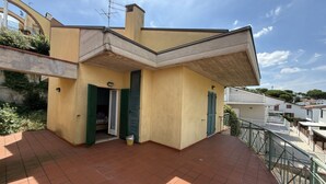 A yellow building with a sloped roof, green shutters, and a tiled patio area. -  M472 - Marcelli, comfortable terraced house near the sea (Marcelli)