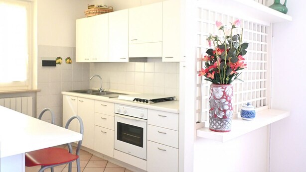A kitchen with white cabinets, a stove, and a sink. There is a vase with flowers on the counter. -  M472 - Marcelli, comfortable terraced house near the sea (Marcelli)