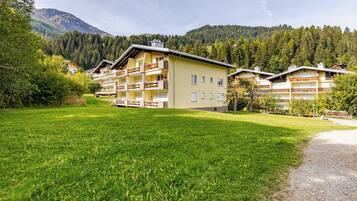 Un hôtel doté de nombreux balcons, d’une pelouse bien entretenue et offrant une vue sur un paysage montagneux.