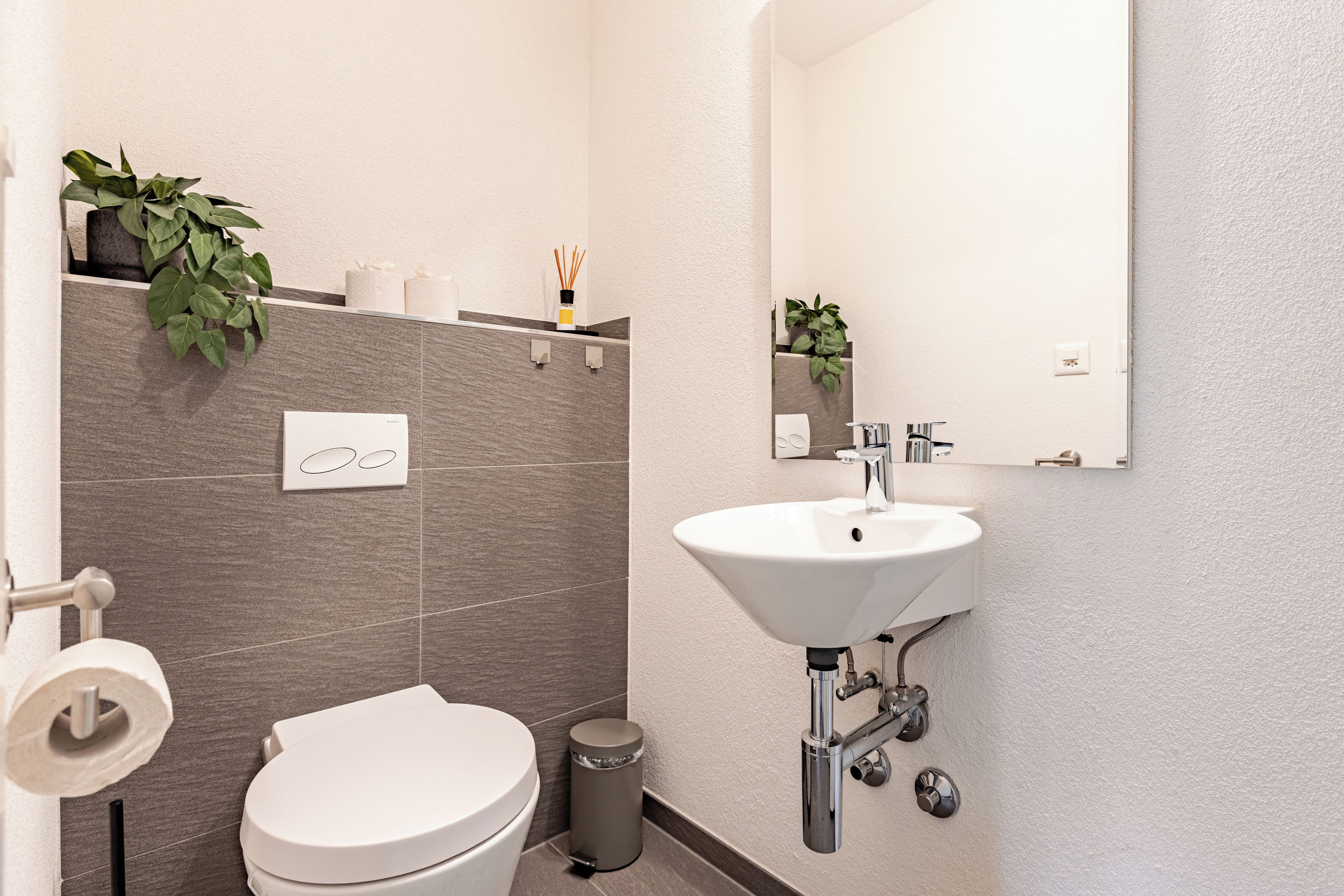 Ein modernes Badezimmer mit Toilette, Waschbecken und Spiegel.