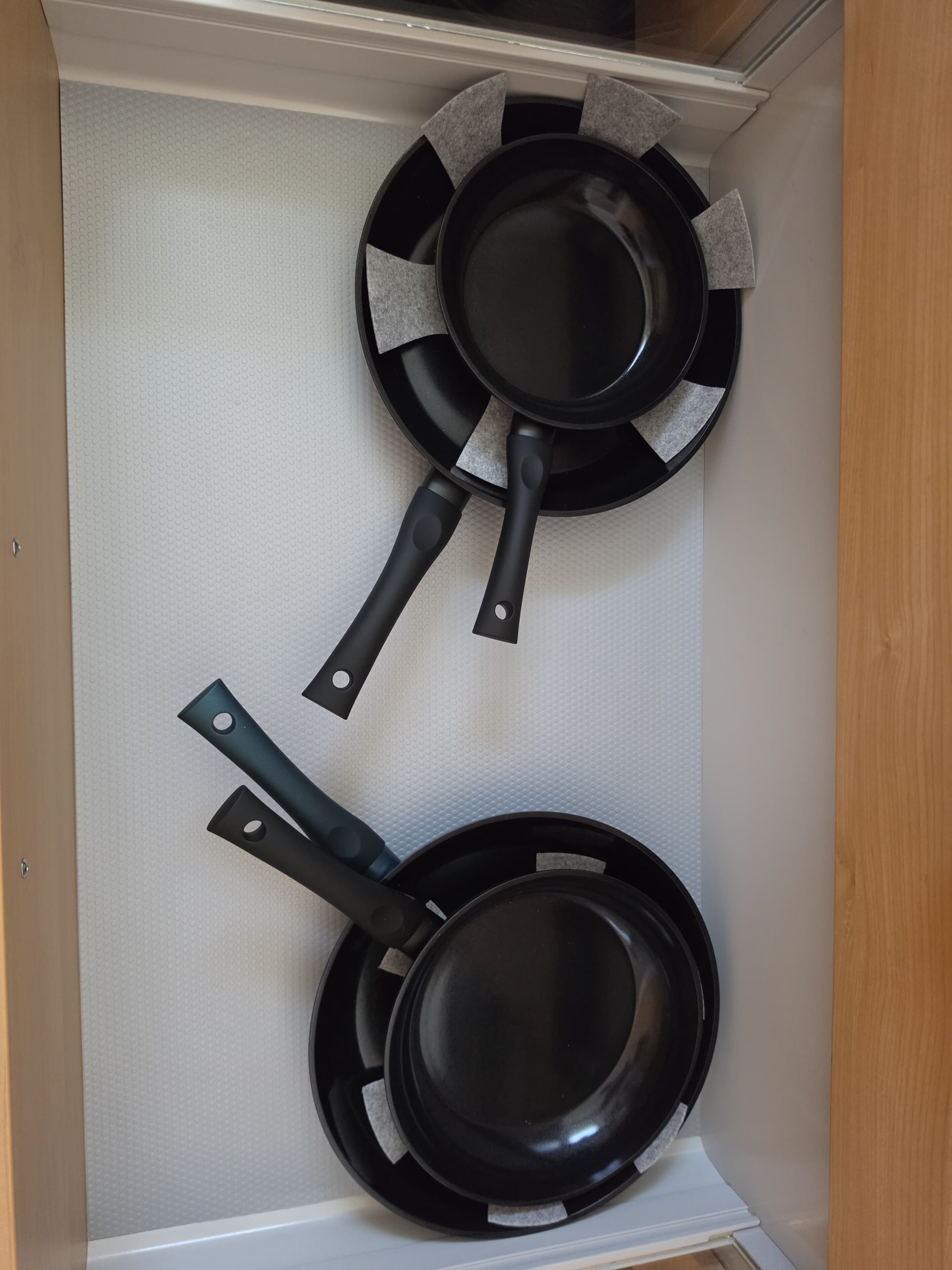 A kitchen with two black frying pans hanging on a white textured wall.