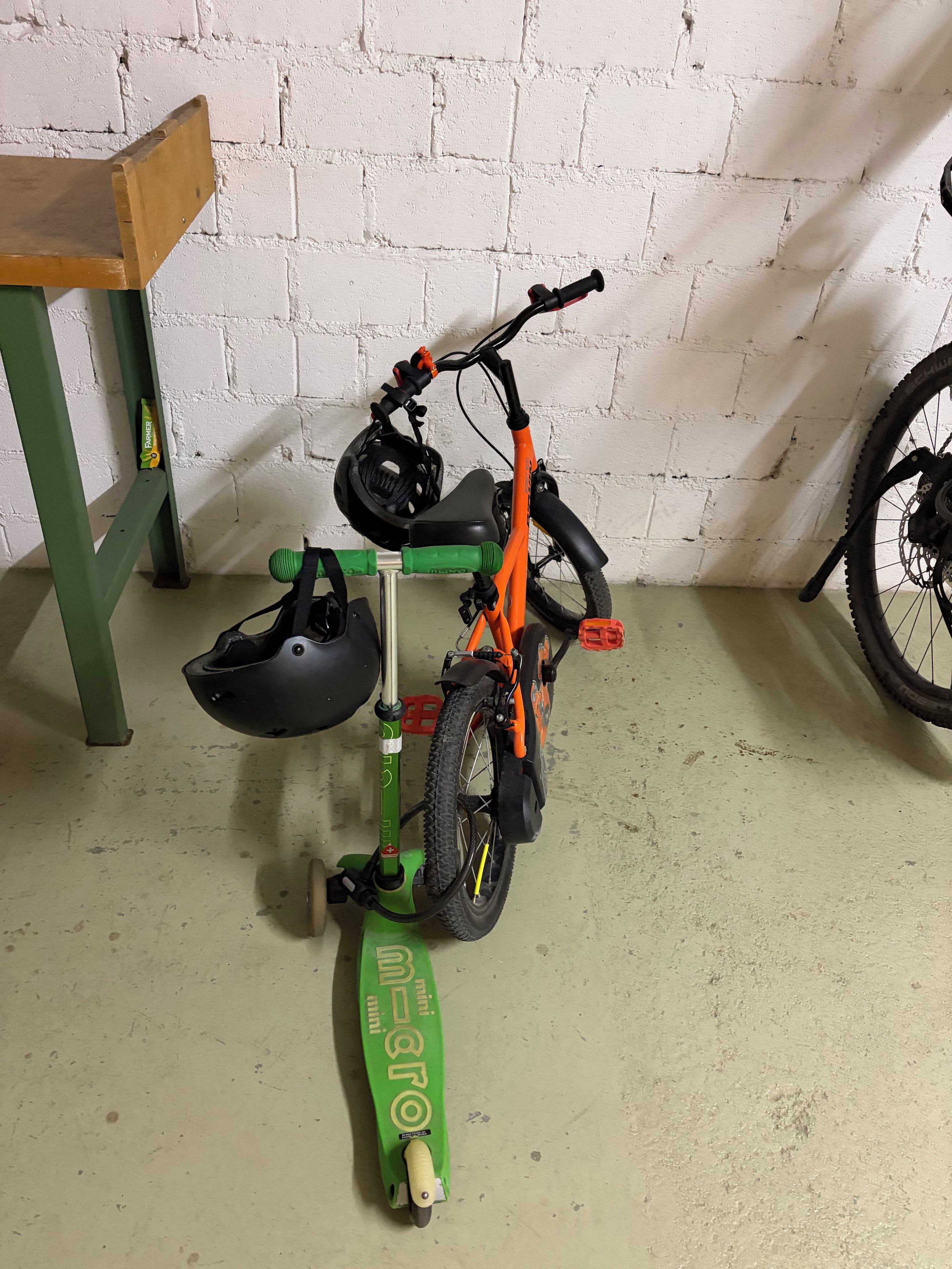 A bicycle with a green stand and a helmet hanging on the stand.
