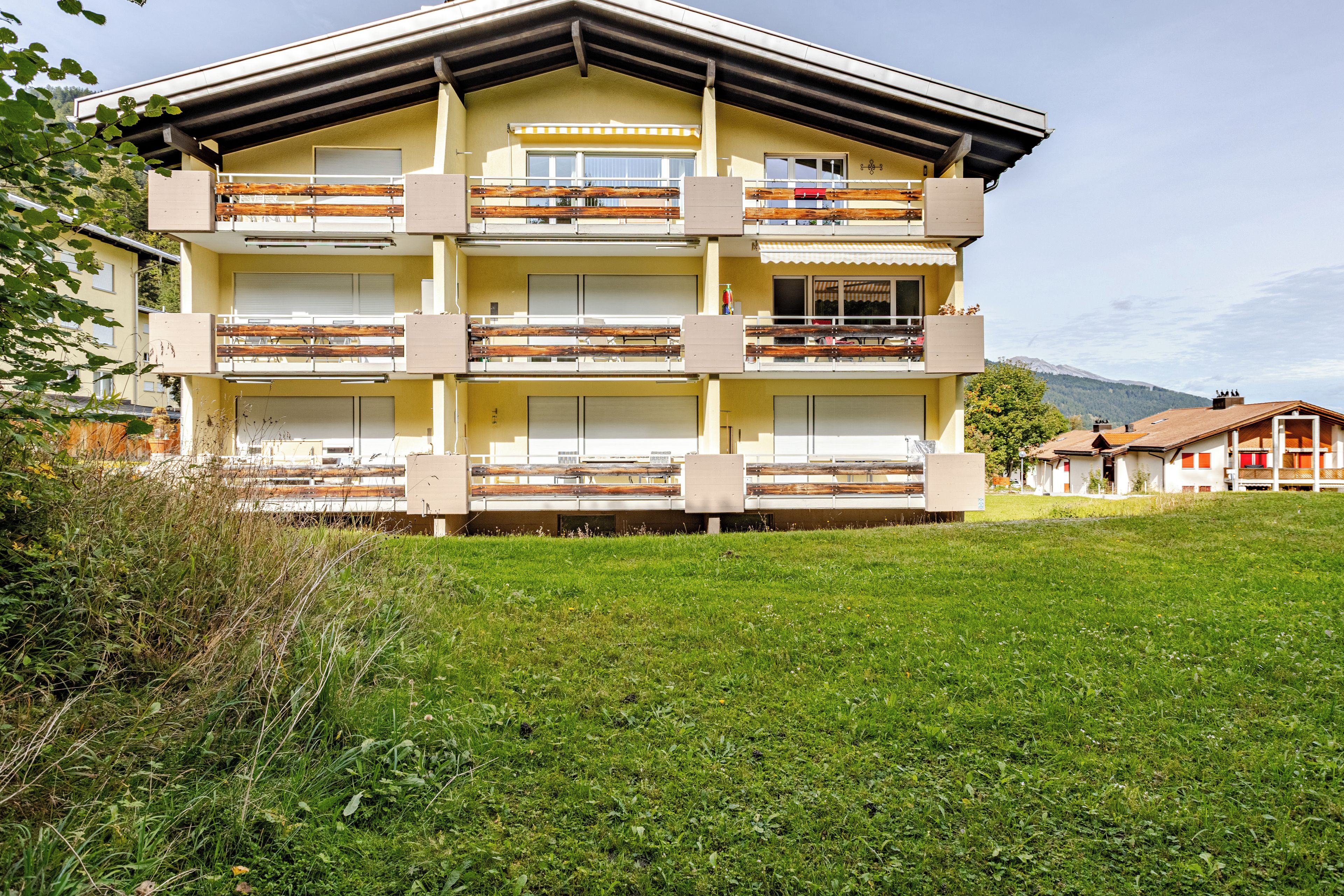 Un immeuble à plusieurs étages, doté de balcons, d’un toit plat et d’un parterre gazonné à l’avant.