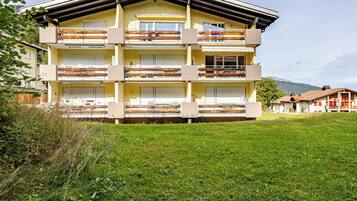 Un immeuble à plusieurs étages, doté de balcons, d’un toit plat et d’un parterre gazonné à l’avant.