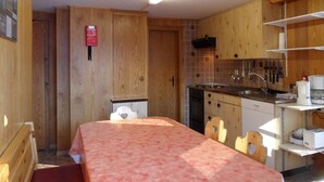Cocina compacta con armarios de madera, un lavamanos y un comedor con mesa y sillas.