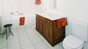 A bathroom with a white sink, wooden cabinet, toilet, and a shower area. - Edelweiss, (Grächen), 5051 by Interhome (Grächen)