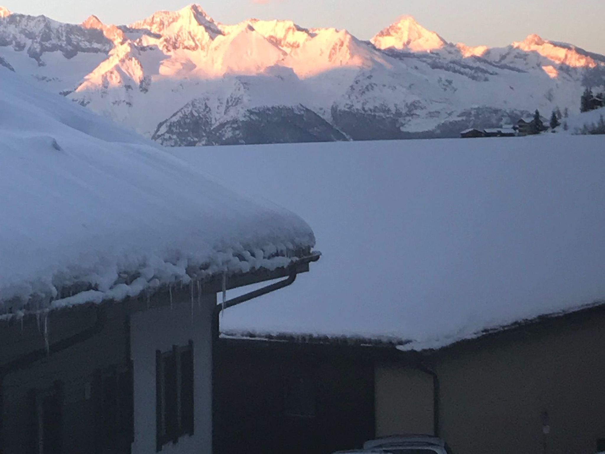A snow-covered mountain range with a building in the foreground.