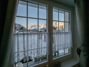 Ein Fenster mit Blick auf schneebedeckte Berge und eine Chalet.