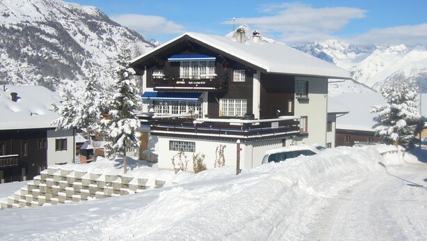 A two-story chalet with a ski lift in the background, surrounded by snow-covered mountains. - Edelweiss, (Grächen), 5051 by Interhome (Grächen)