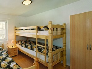 Ein Etagenbett mit Blumenmuster-Bettwäsche, ein Nachttisch mit Lampe und ein Kleiderschrank.