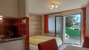 Un dormitorio con cama, una mesa de comedor y una zona de cocina con cafetera.