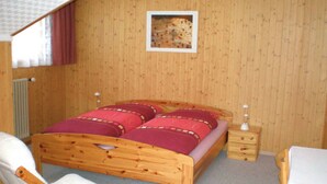 A wooden room with a bed, a chair, a nightstand, and a table. - Chalet Matten, (Grächen), by Interhome (Grächen)