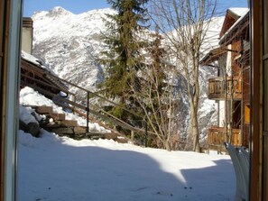 A snowy mountain landscape with a wooden building featuring balconies. - Alicia, (Grächen), 1901 by Interhome (Grächen)
